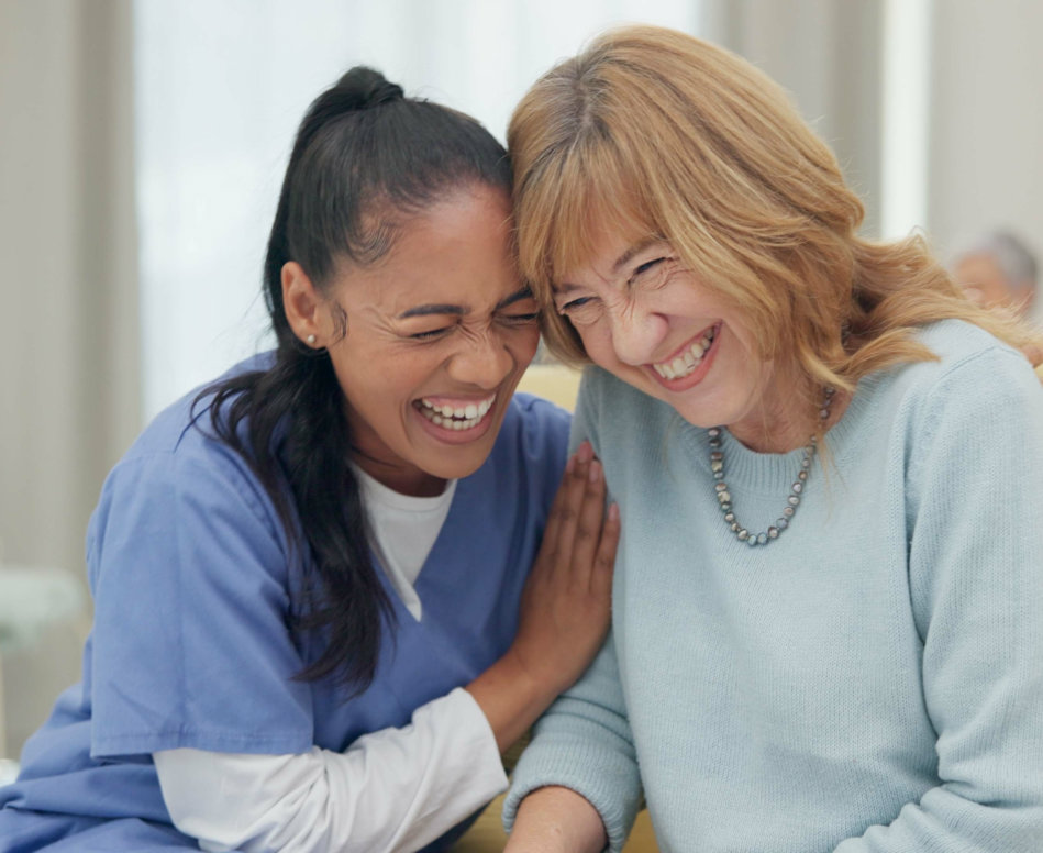 caregiver laughing together with senior woman